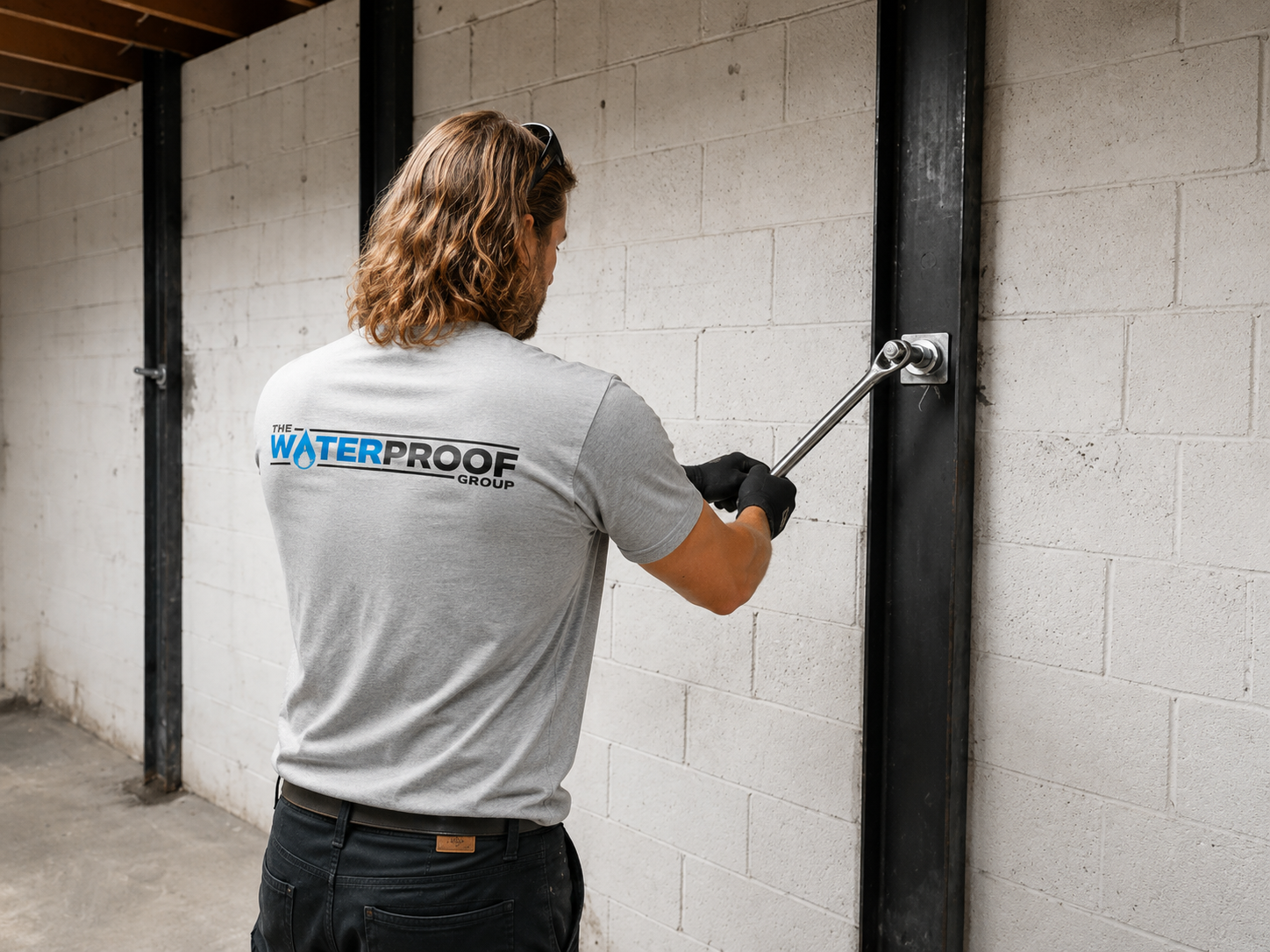 tightening helical wall anchor Technicians applying waterproofing membrane with sprayer