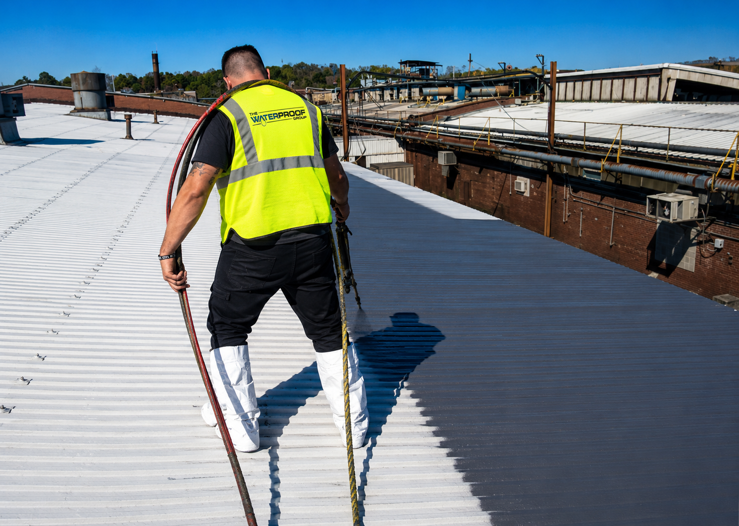 Technicians applying waterproofing membrane with sprayer