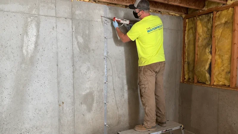 Technician injecting a foundation wall crack in a Metro Atlanta basement